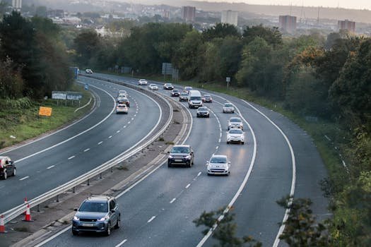 Cars traveling on a highway with a backdrop of Bristol city buildings and lush greenery.